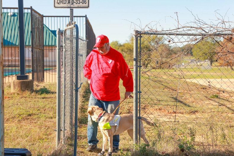 Charles and his guide dog Tango walking through a fence gate together