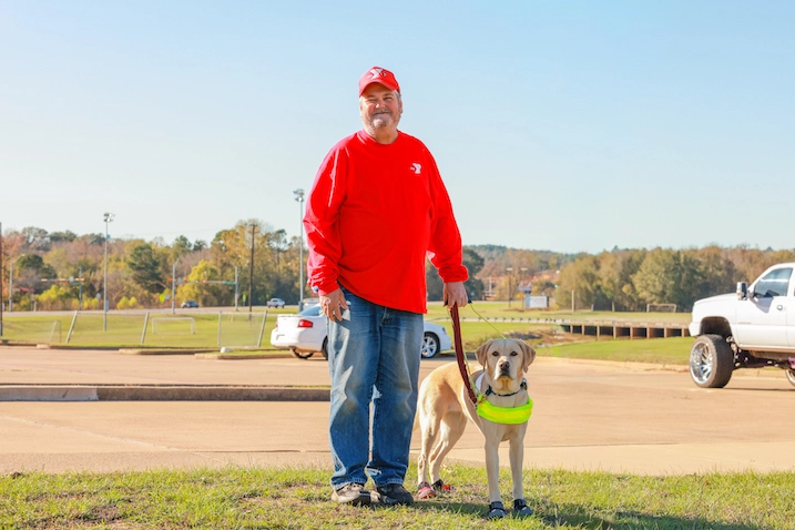 Charles and his guide dog Tango standing next to each other in the grass