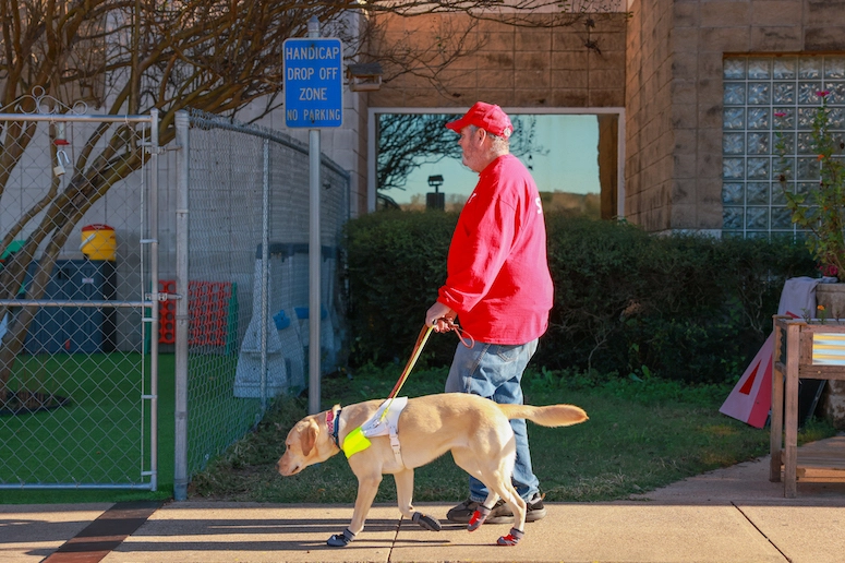 Charles and his guide dog Tango walking down the sidewalk together